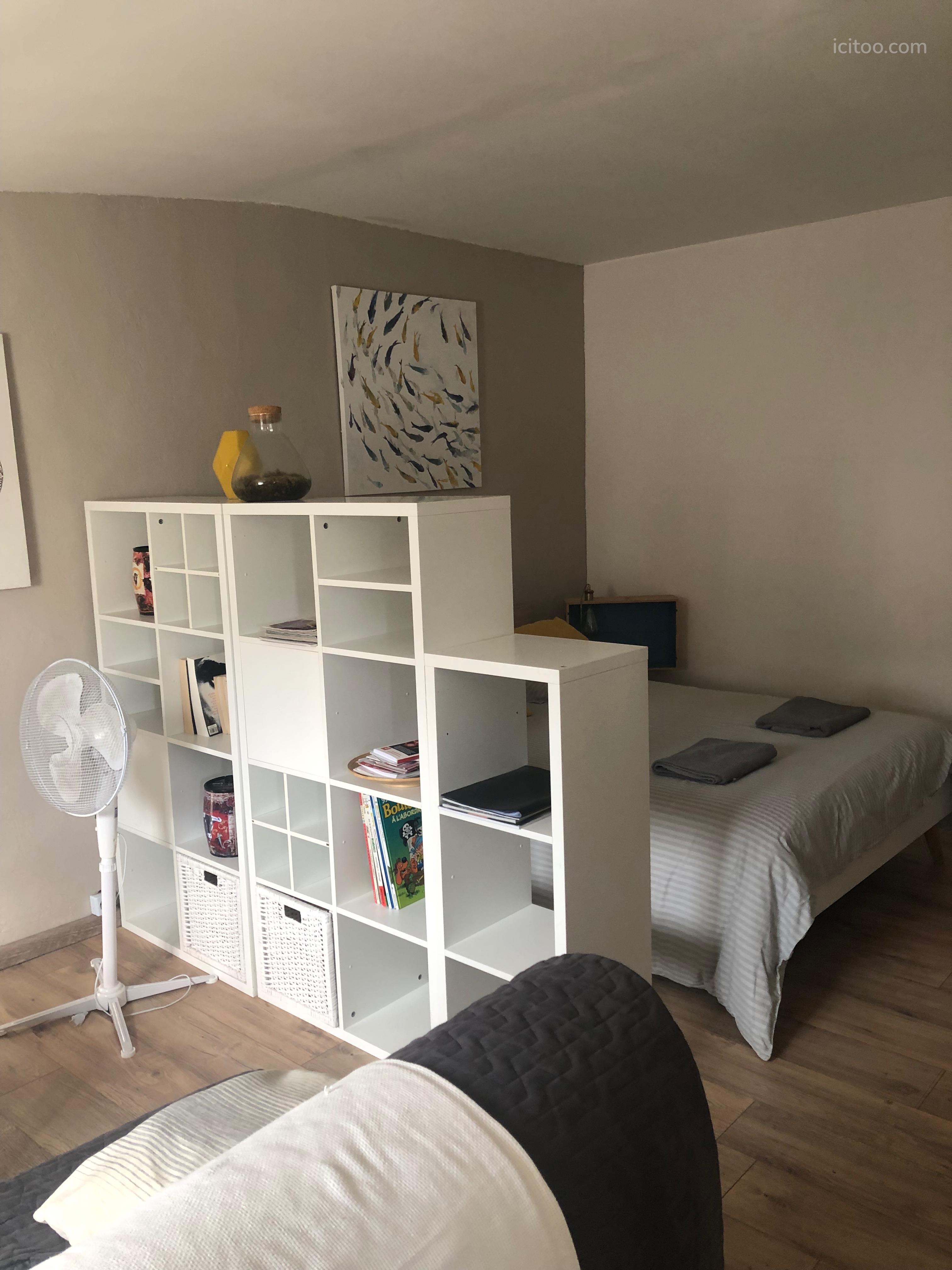 Studio meublé avec lit double et étagère de rangement dans un appartement à louer à Nîmes