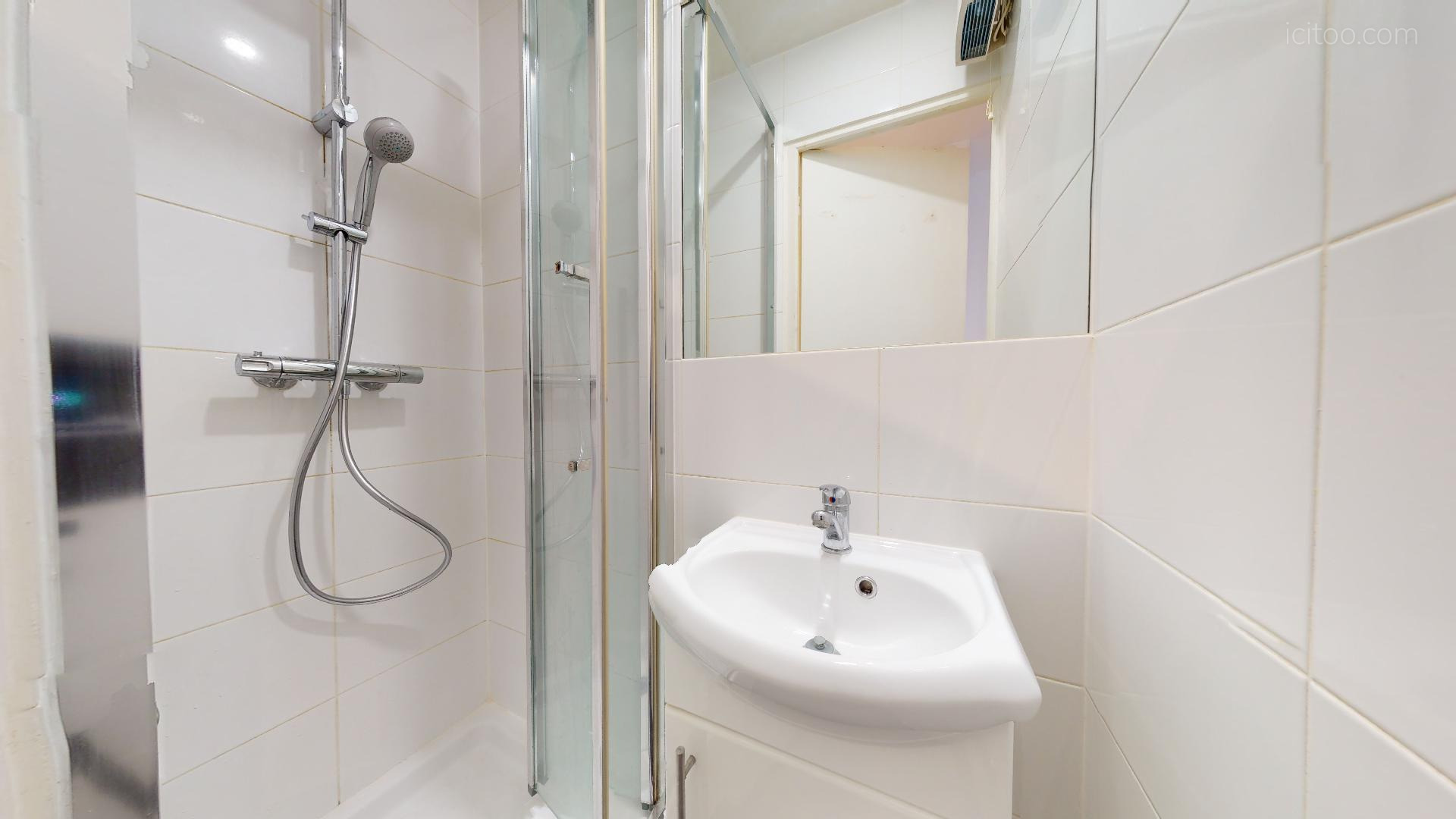 Studio à louer Paris 14m² : salle de bain avec douche, meuble vasque et miroir.