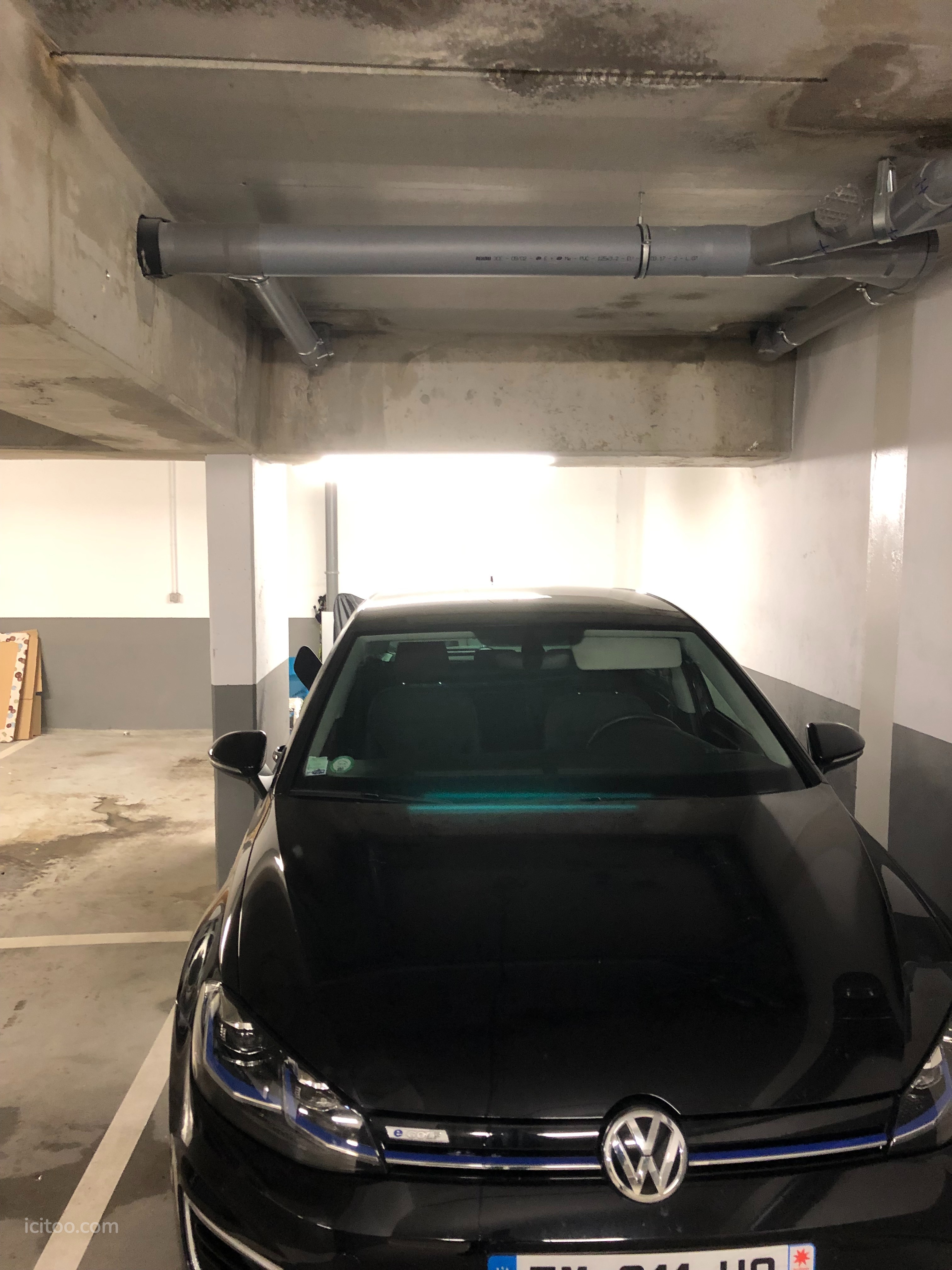 Intérieur d'un parking sécurisé à Bougival montrant une voiture garée près d'une prise électrique.