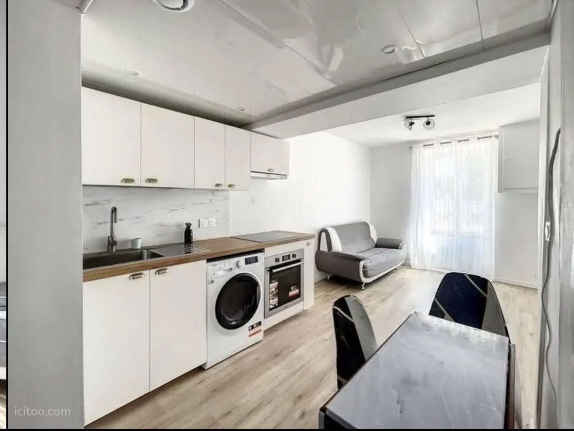 Appartement T3 à louer Mulhouse : cuisine aménagée et séjour lumineux avec voilages.