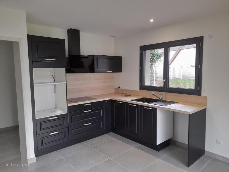 Cuisine équipée moderne avec meubles sombres et plan de travail clair, maison à louer à Renaison