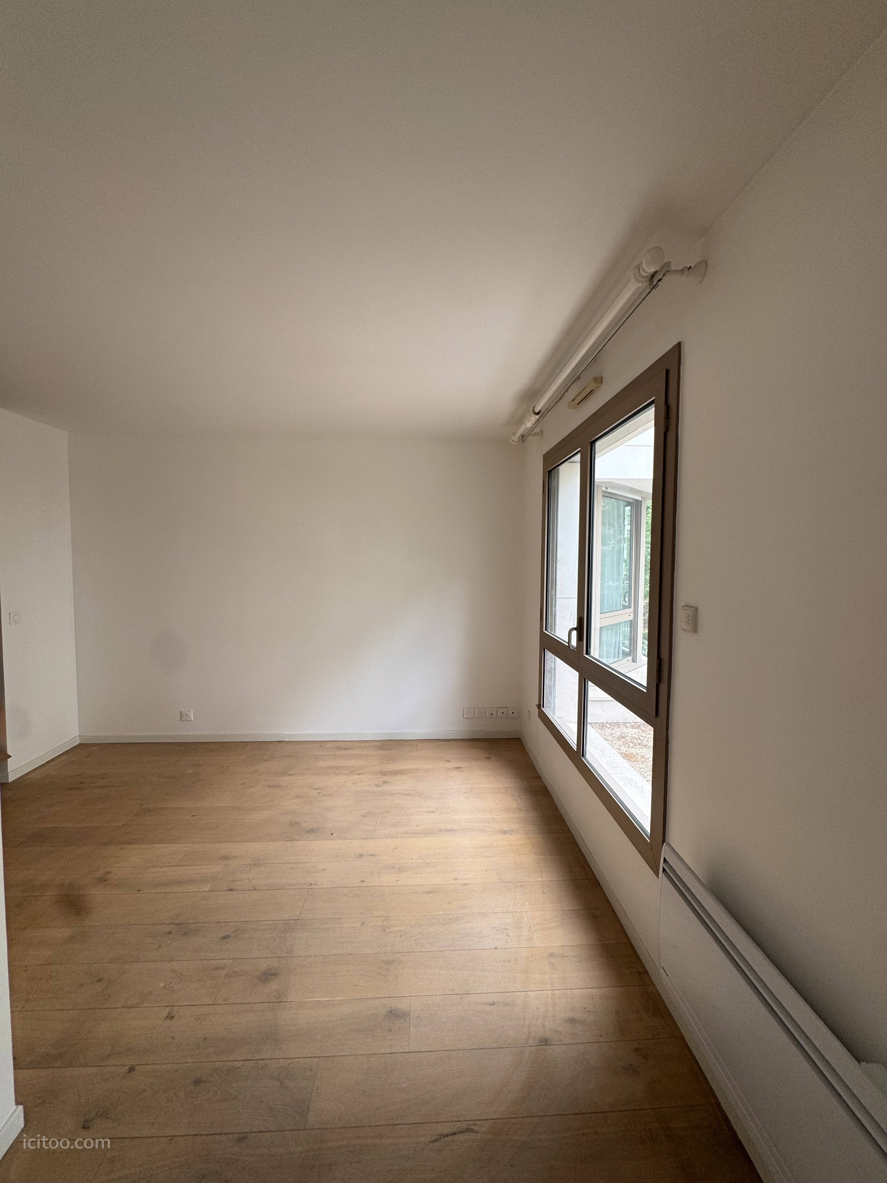Grand séjour lumineux avec parquet en bois et large fenêtre, appartement à vendre à Levallois-Perret.
