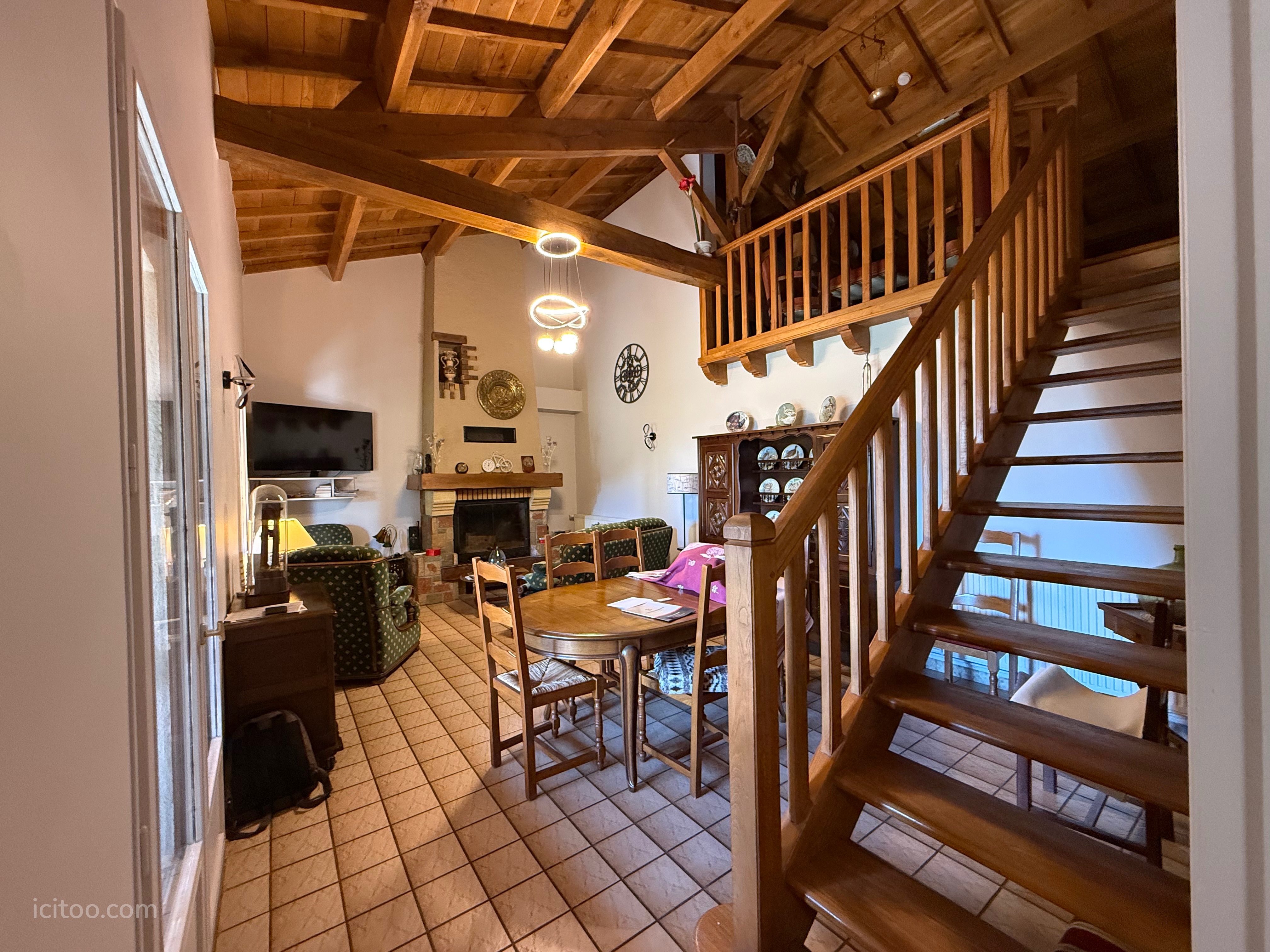 Salon spacieux avec cheminée, poutres apparentes et escalier en bois, maison à vendre à Landorthe.