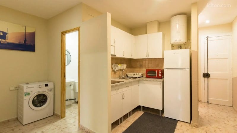 Cuisine aménagée avec meubles blancs, réfrigérateur et lave-linge dans un appartement à louer à Reims