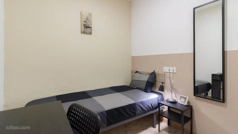 Vue d'une chambre meublée avec un lit simple, un bureau et un miroir dans un appartement à louer à Reims