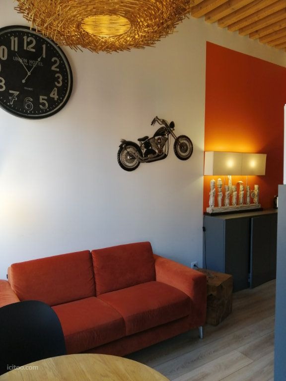 Salon d'un appartement meublé à louer à Lyon 69001 avec canapé orange et décoration murale.