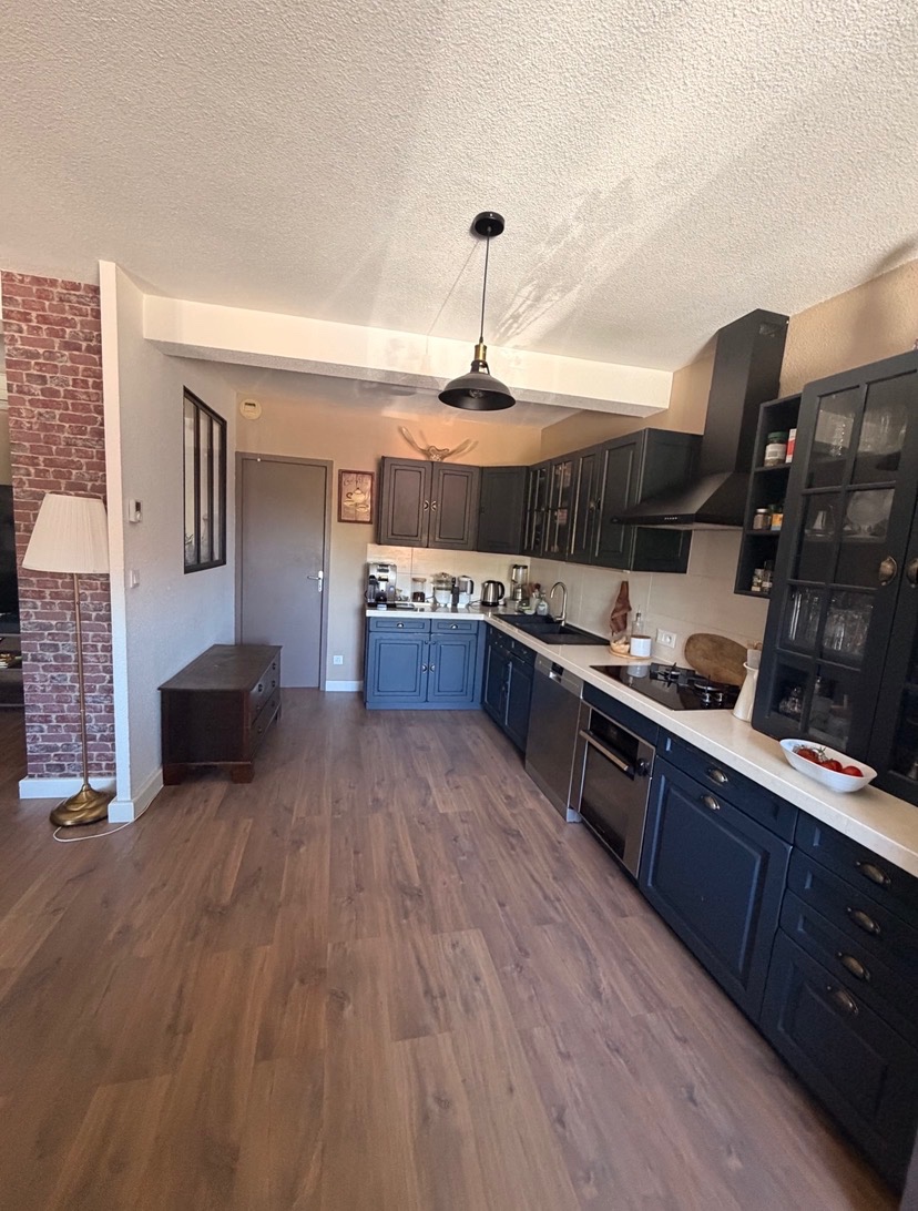 Appartement T4 à vendre à Feyzin 69320, cuisine ouverte équipée noire avec plan de travail et électroménager.
