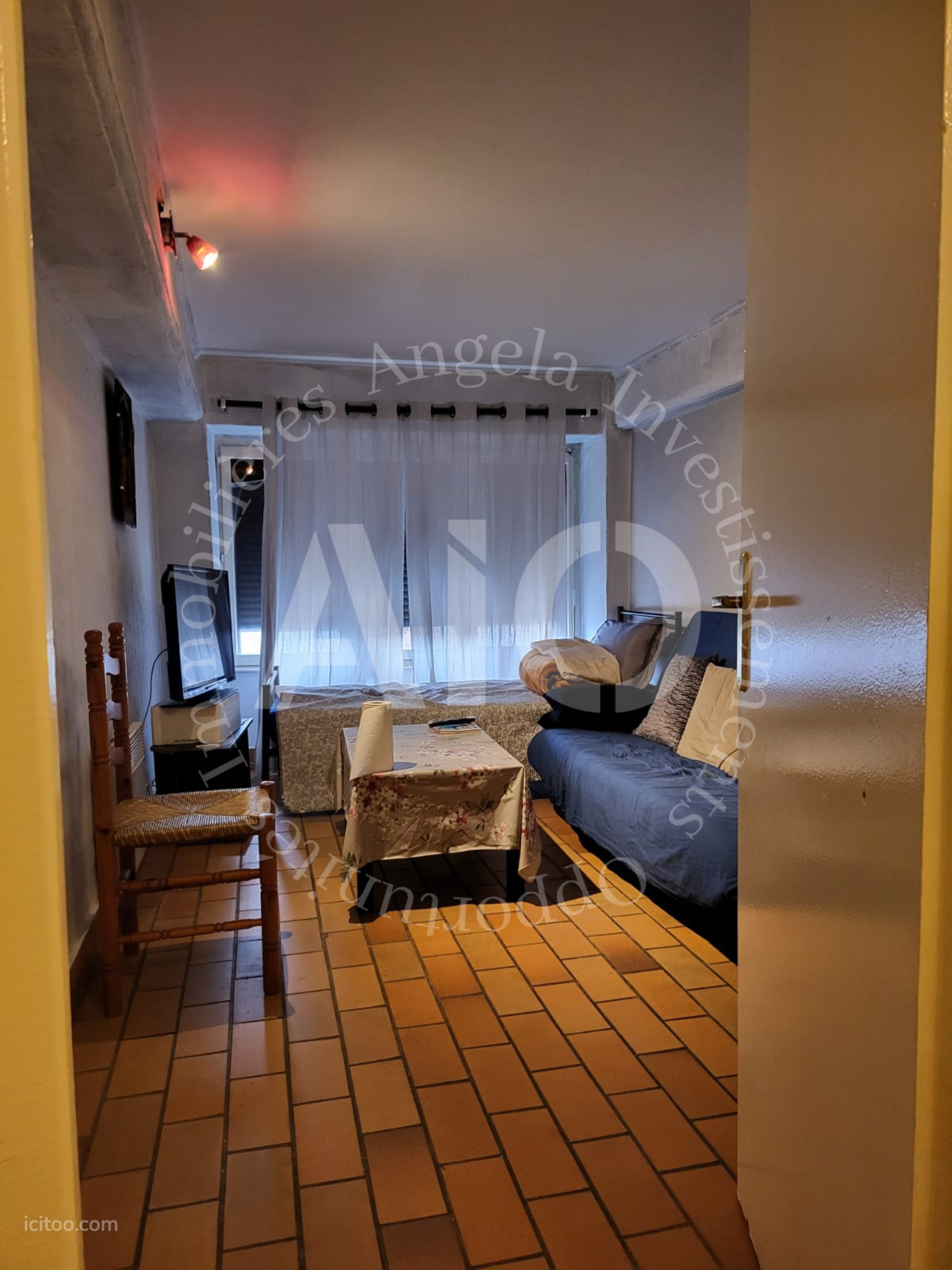 Séjour d'un appartement à Caluire-et-Cuire avec canapé bleu, table basse, télévision et sol en carrelage.