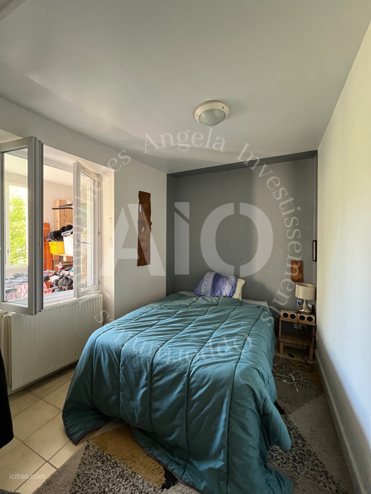 Chambre avec lit double, table de chevet et fenêtre ouverte sur l'extérieur, appartement à vendre à Vindry-sur-Turdine.