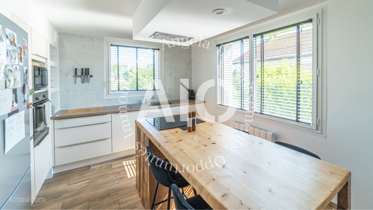 Cuisine aménagée moderne avec îlot central et fenêtres, maison à vendre à Péronnas.