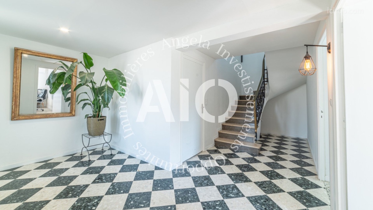 Entrée spacieuse avec carrelage damier noir et blanc et escalier, maison à vendre à Péronnas.