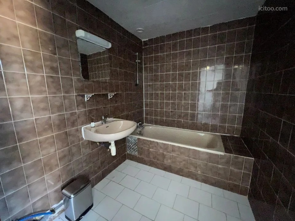 Salle de bain carrelée de couleur marron avec baignoire, lavabo et miroir, appartement à vendre à Avignon.
