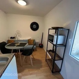 Studio aménagé avec coin salon, table et chaises, et étagère cuisine, appartement à vendre à Avignon.